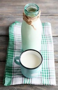 Glass bottle of milk on wooden background
